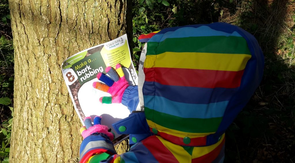 My daughter tries one of the activities on the Stick Man trail, bark rubbing on a day out in Buckinghamshire with kids at Wendover Woods