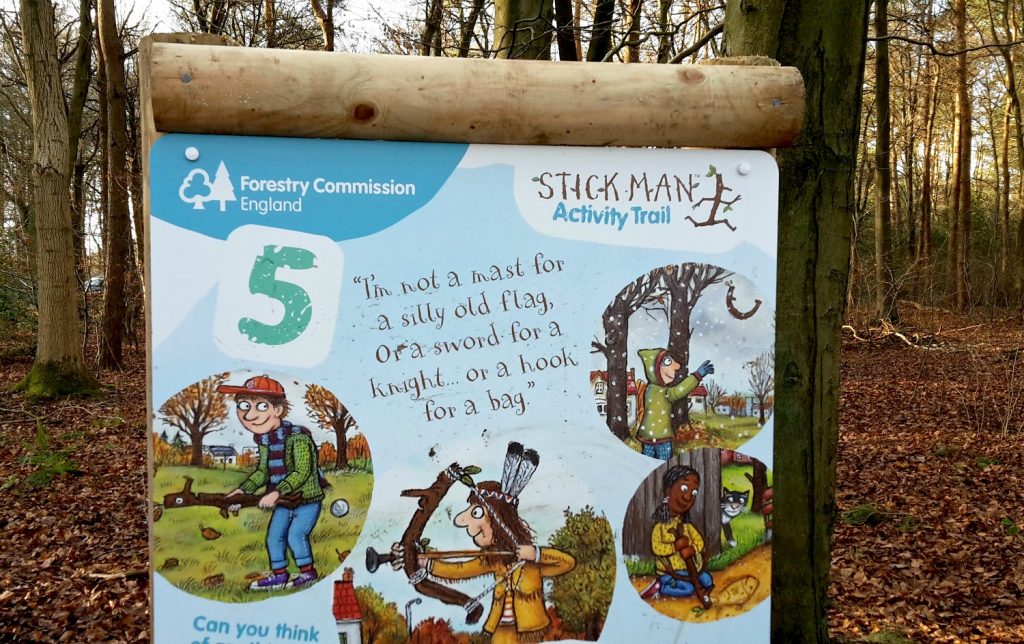 My daughter looks at one of the signs on the Stick Man trail on a family day out in Buckinghamshire, at Wendover Woods