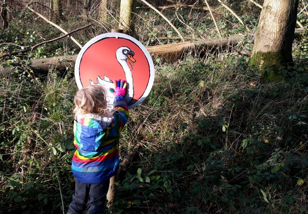 My daughter with a swan sign on the Stick Man trail at Wendover Woods - one of my favourite family days out in Buckinghamshire