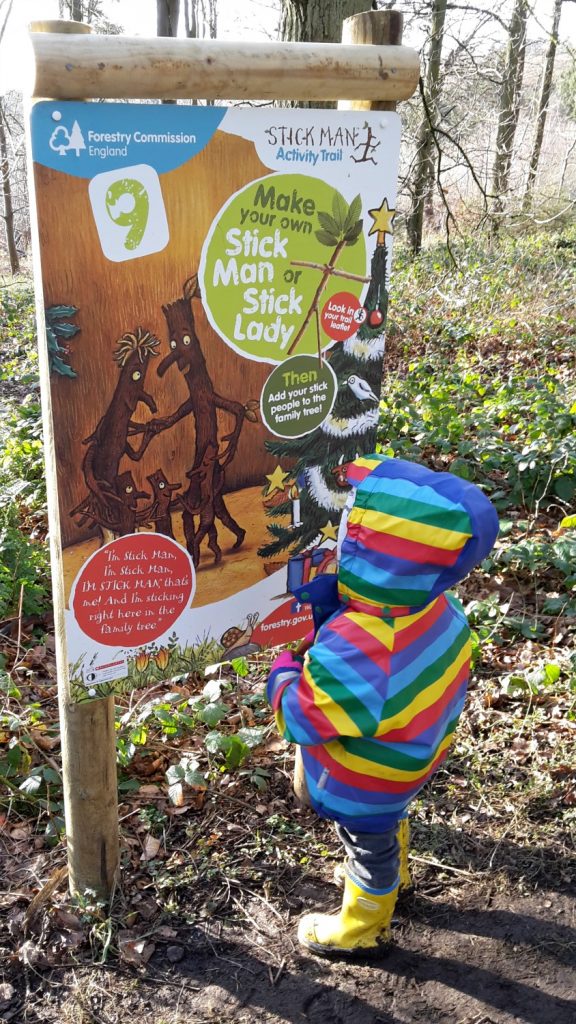 My daughter looks at one of the signs on the Stick Man trail on a family day out in Buckinghamshire, at Wendover Woods