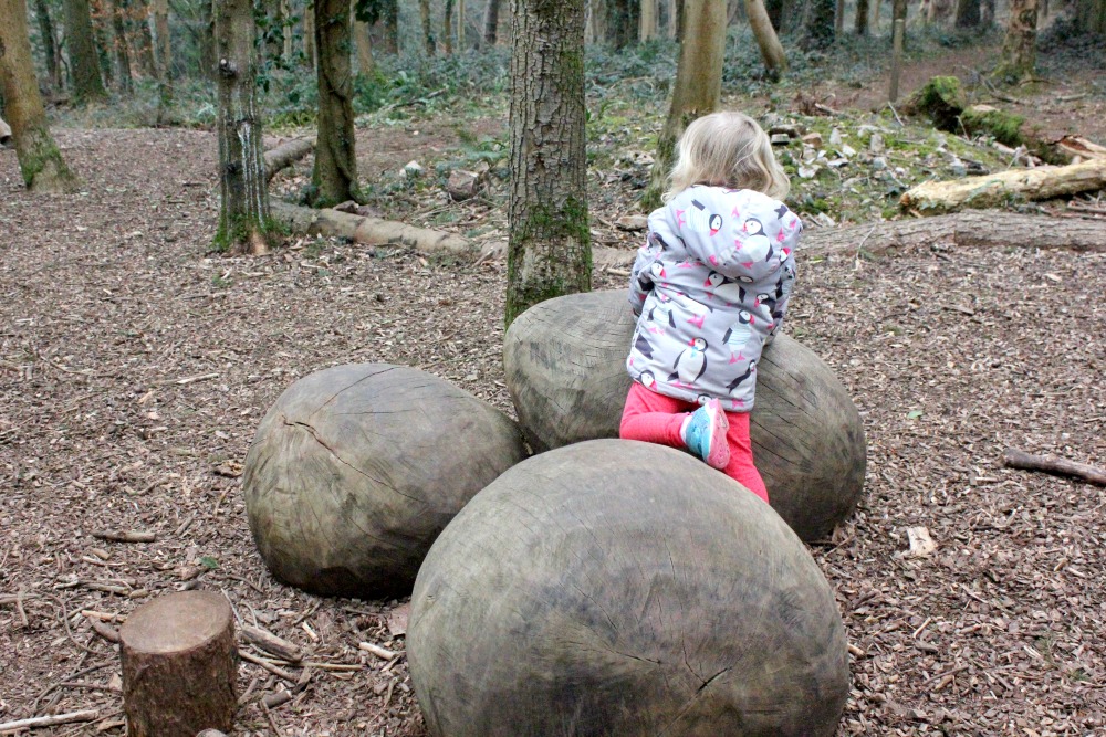 My daughter clambers over huge round objects in the Tyntesfield play area