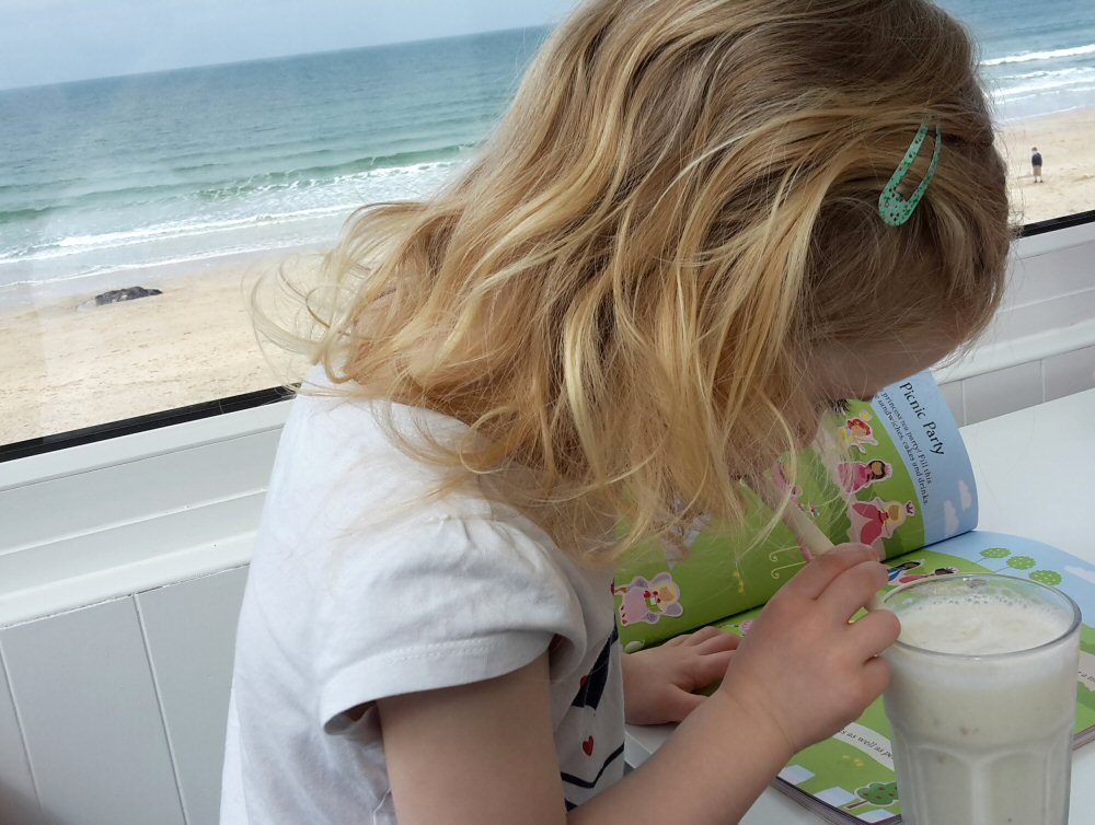 My daughter in the family-friendly Porthmeor cafe in St Ives, Cornwall, with some of the free activities and a view of the beach