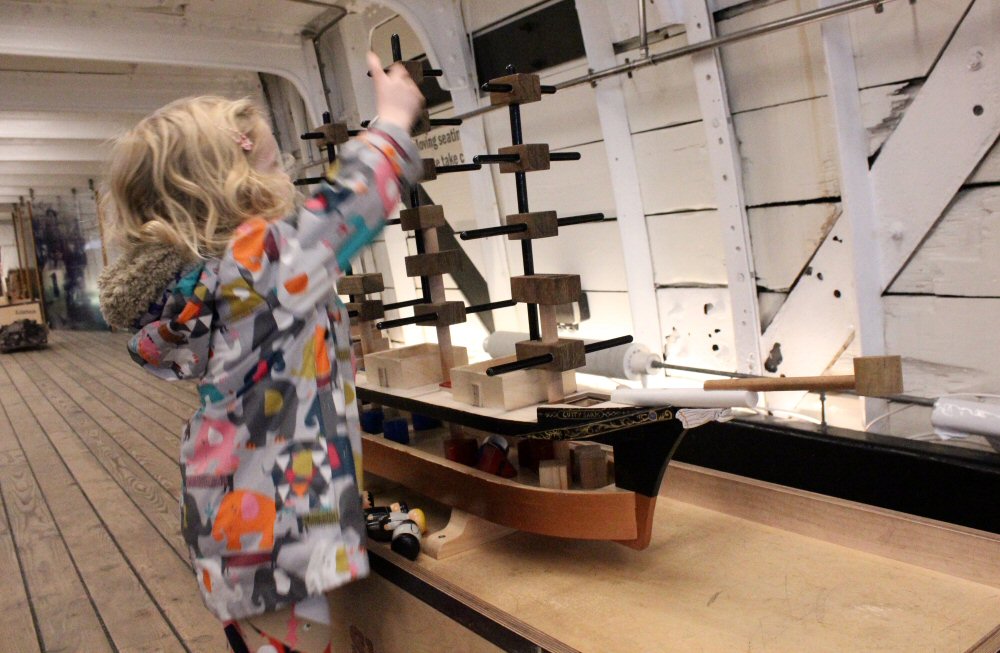 My daughter touches a model boat at the Cutty Sark