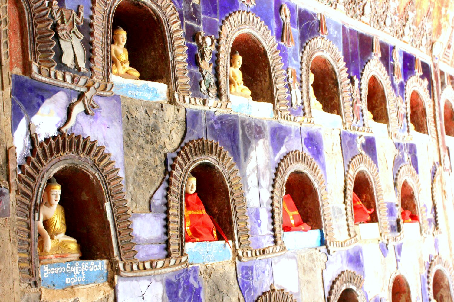 Small Buddha statues in gold and bright colours in tiled niches in glossy purple. With Burma newly opened up to tourists, and off the beaten track for most families, here are my 12 reasons to visit Burma (Myanmar) - in photos