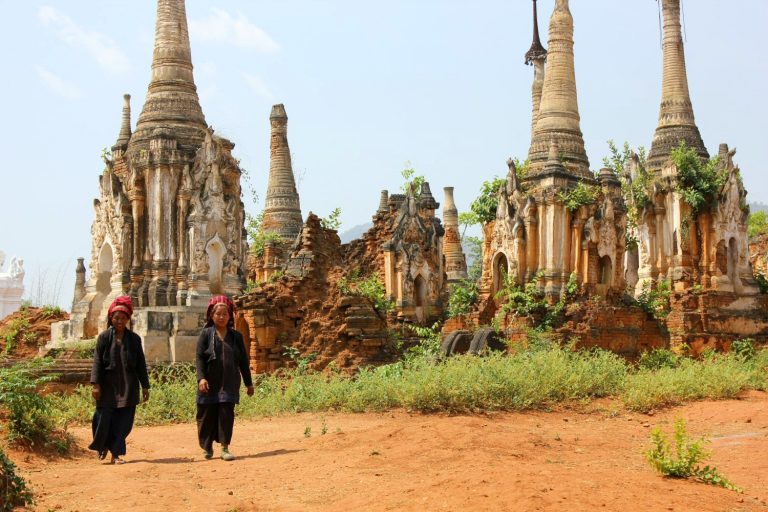 Two Intha women walking through the stupas of In Dein, by Inle Lake - - one of the top things to do at Inle Lake with kids