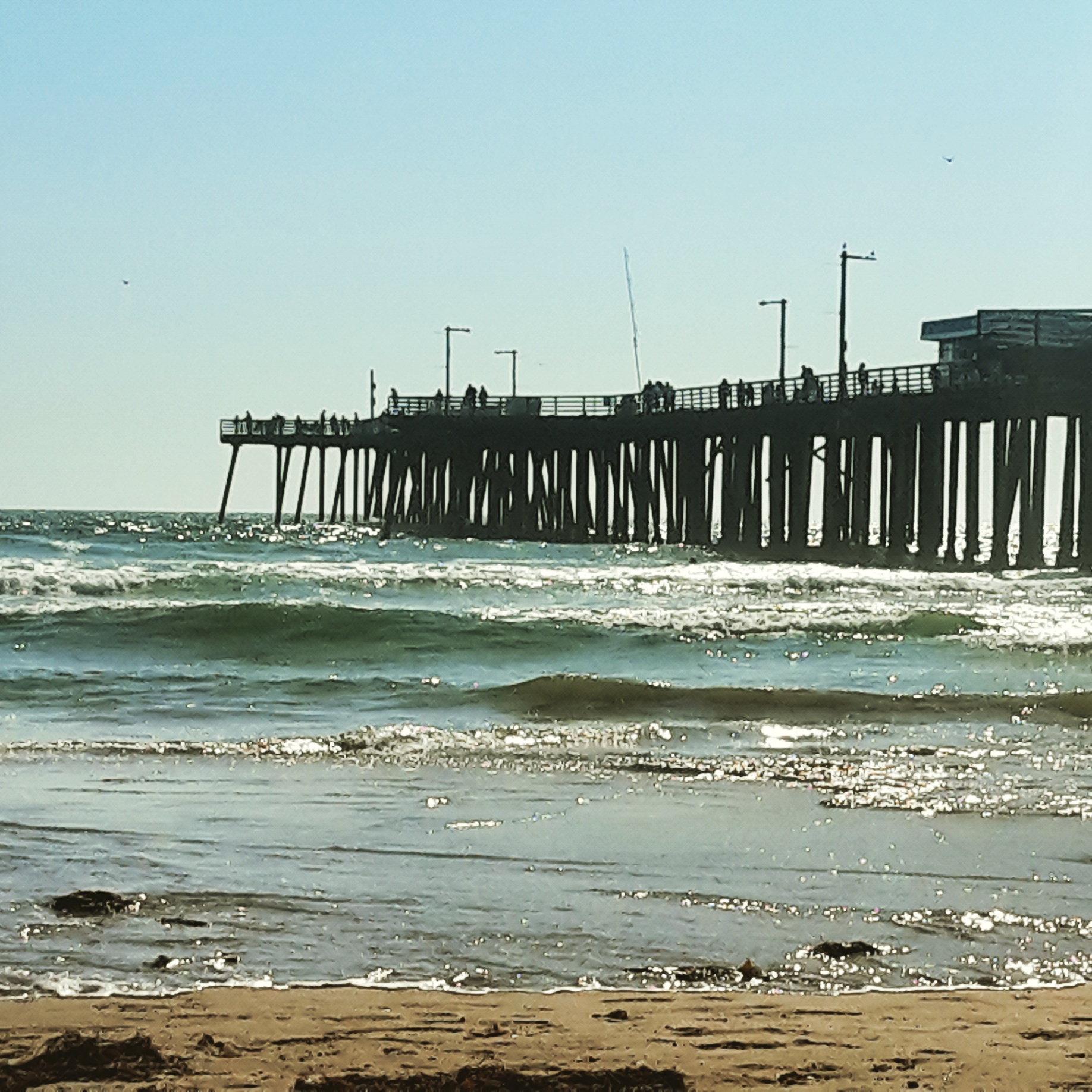Pismo Beach pier with the sun reflected on the waves in California on the last stop of our Pacific Coast Highway itinerary - how to do a California road trip with kids