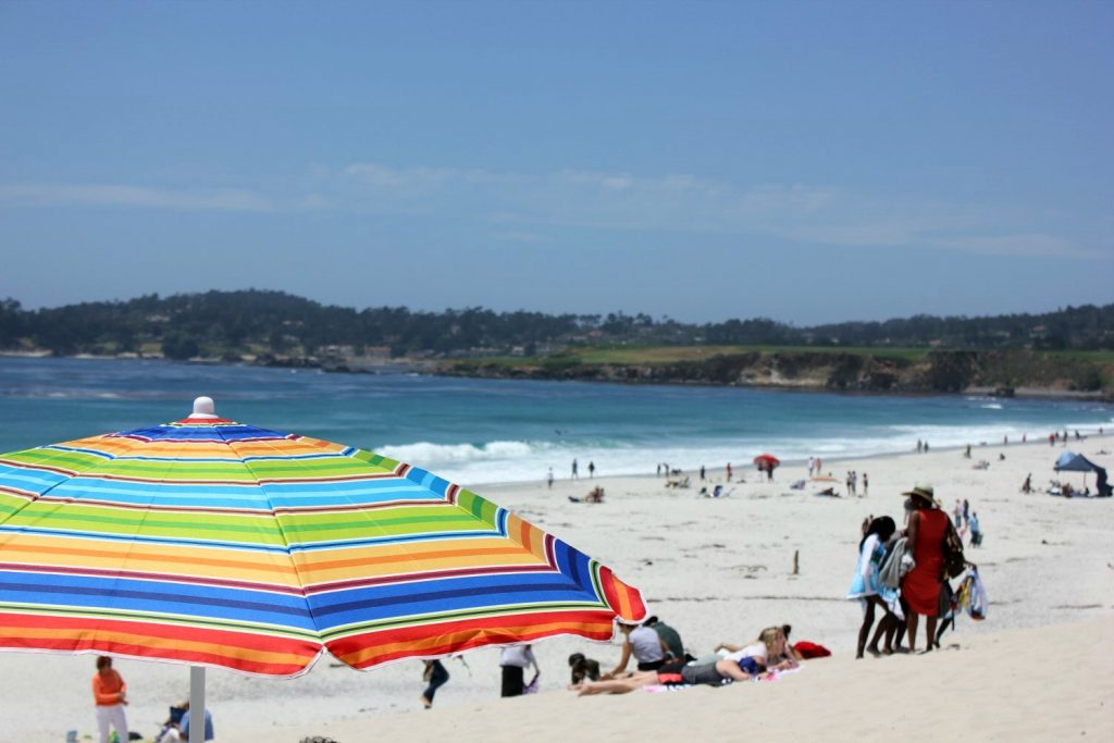 View of the beach including a rainbow coloured parasol at Carmel - my Pacific Coast Highway pictures and reasons to visit California
