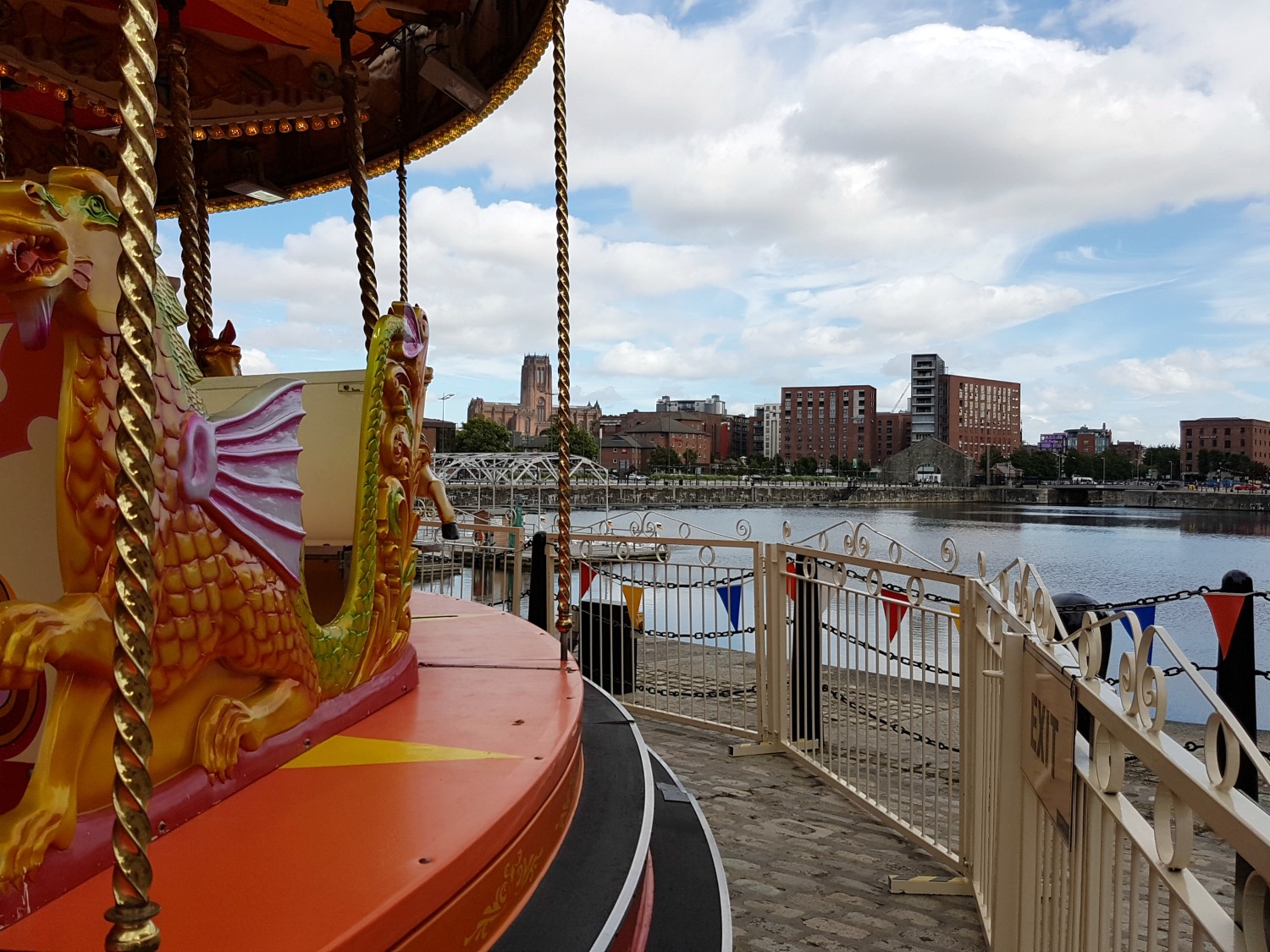 View across the carousel to the water and buildings beyond Albert Dock, Liverpool - exploring the Albert Docks kids' attractions. and my Albert Dock review