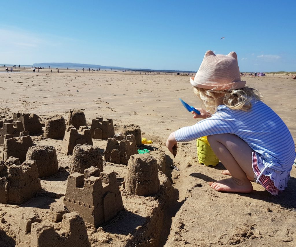 Girl making sandcastles on Camber Sands beach in East Sussex - spending a weekend in East Sussex with my daughter before the start of school, to explore the history and coastline