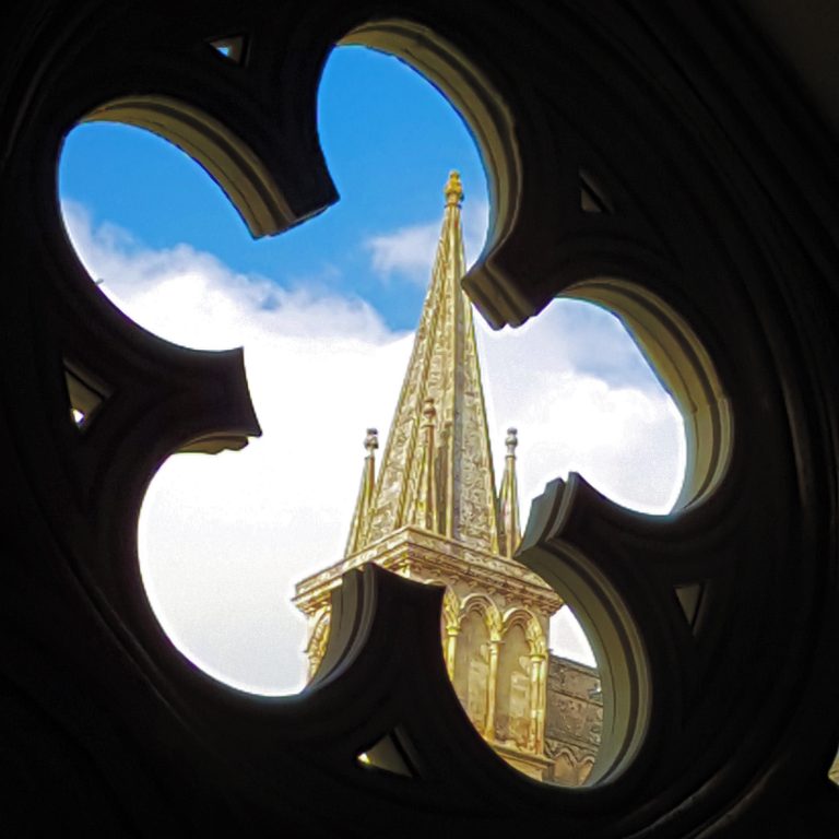 A view of the spire of Salisbury cathedral through one of the flower-shaped cloister windows - my visit to Salisbury cathedral with kids