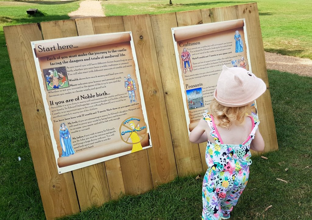 My daughter playing the medieval Game of Life at Bodiam Castle in East Sussex - my review and why it's great to visit Bodiam Castle with kids