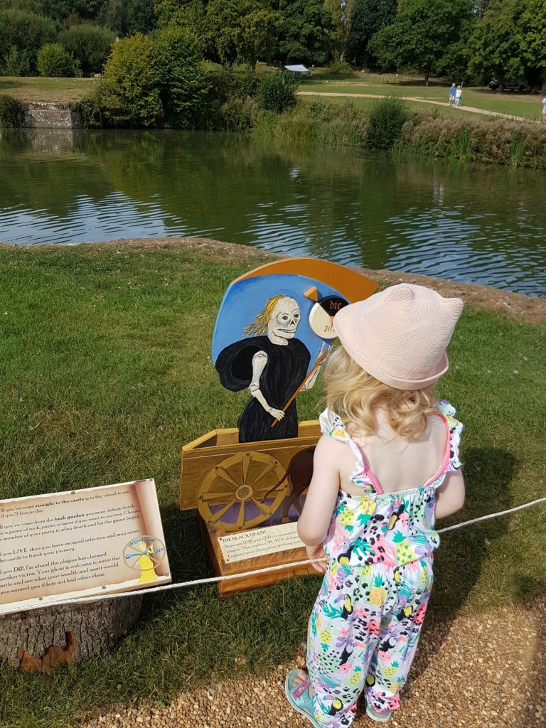 My daughter playing the medieval Game of Life at Bodiam Castle in East Sussex - my review and why it's great to visit Bodiam Castle with kids