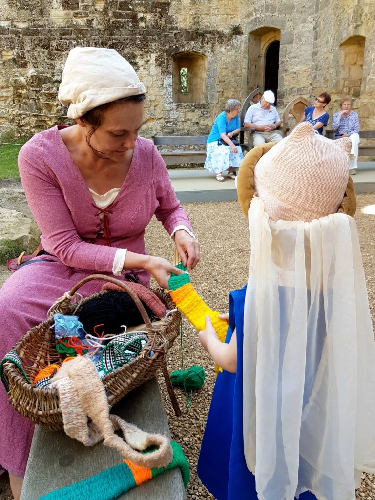 My daughter in medieval dress with a volunteer at Bodiam Castle in East Sussex - my review and why it's great to visit Bodiam Castle with kids