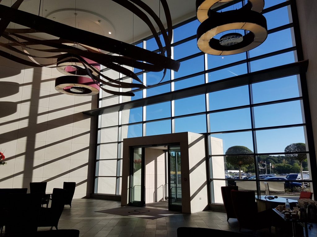 Dramatic shot of the lobby at Brooklands Hotel, Surrey, with its huge deep pink and gold lights against a blue sky - my review of our stay at Brooklands Hotel with kids