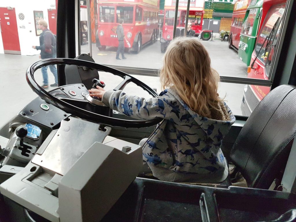 Young girl at the wheel of a classic bus at the London Bus Museum at Brooklands - my review of Brooklands Museum in Surrey after our family day out