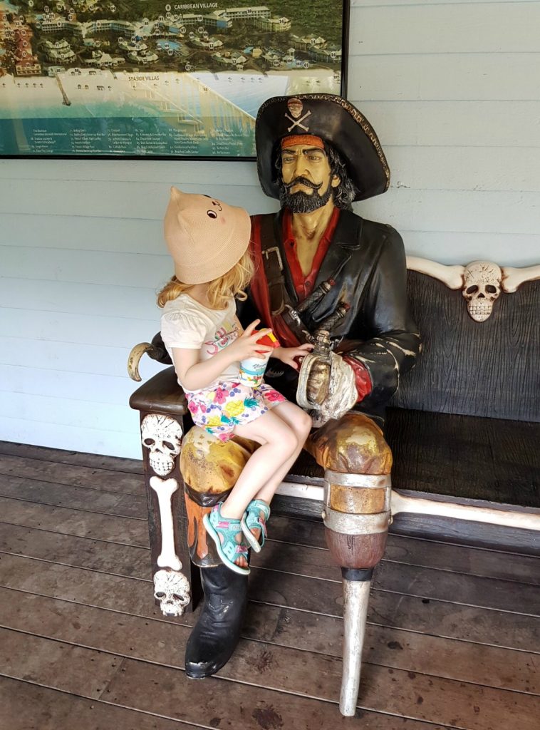 Pirate Island - small girl sits on the knee of the pirate statue by the kids' facilities. - one of my 9 top reasons to visit Beaches Turks & Caicos with kids