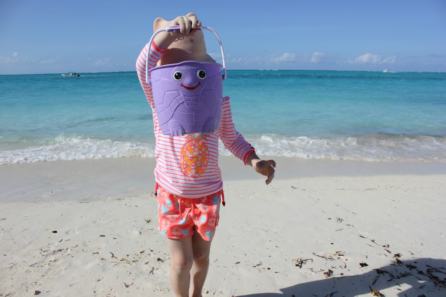 A girl on a beach holding a bucket looks out onto the Caribbean sea - my Sunuva swimwear review