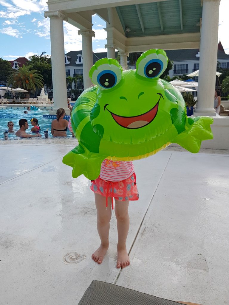 A girl holding an inflatable frog ring in front of a swimming pool at Beaches Resort on Providenciales - my Sunuva swimwear review