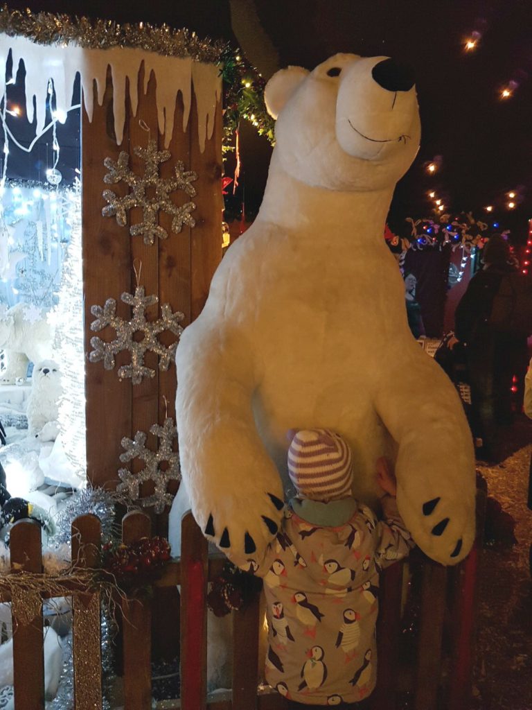 My daughter cuddles a giant polar bear in Santa's Grotto at Willows Activity Farm Santa Spectacular near St Albans in Hertfordshire - my review of our family day out