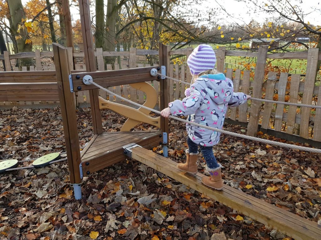 My daughter balances on the play equipment in Peter Rabbit's adventure playground at Willows Activity Farm Santa Spectacular near St Albans in Hertfordshire - my review of our family day out