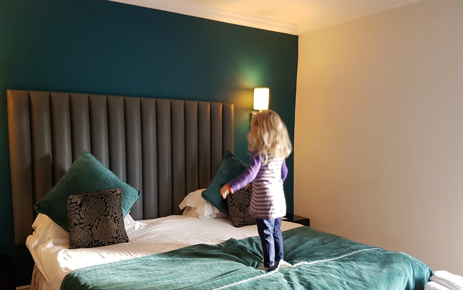 My daughter standing on the huge double bed in our room at Fishmore Hall in Shropshire, UK - a boutique hotel with kids