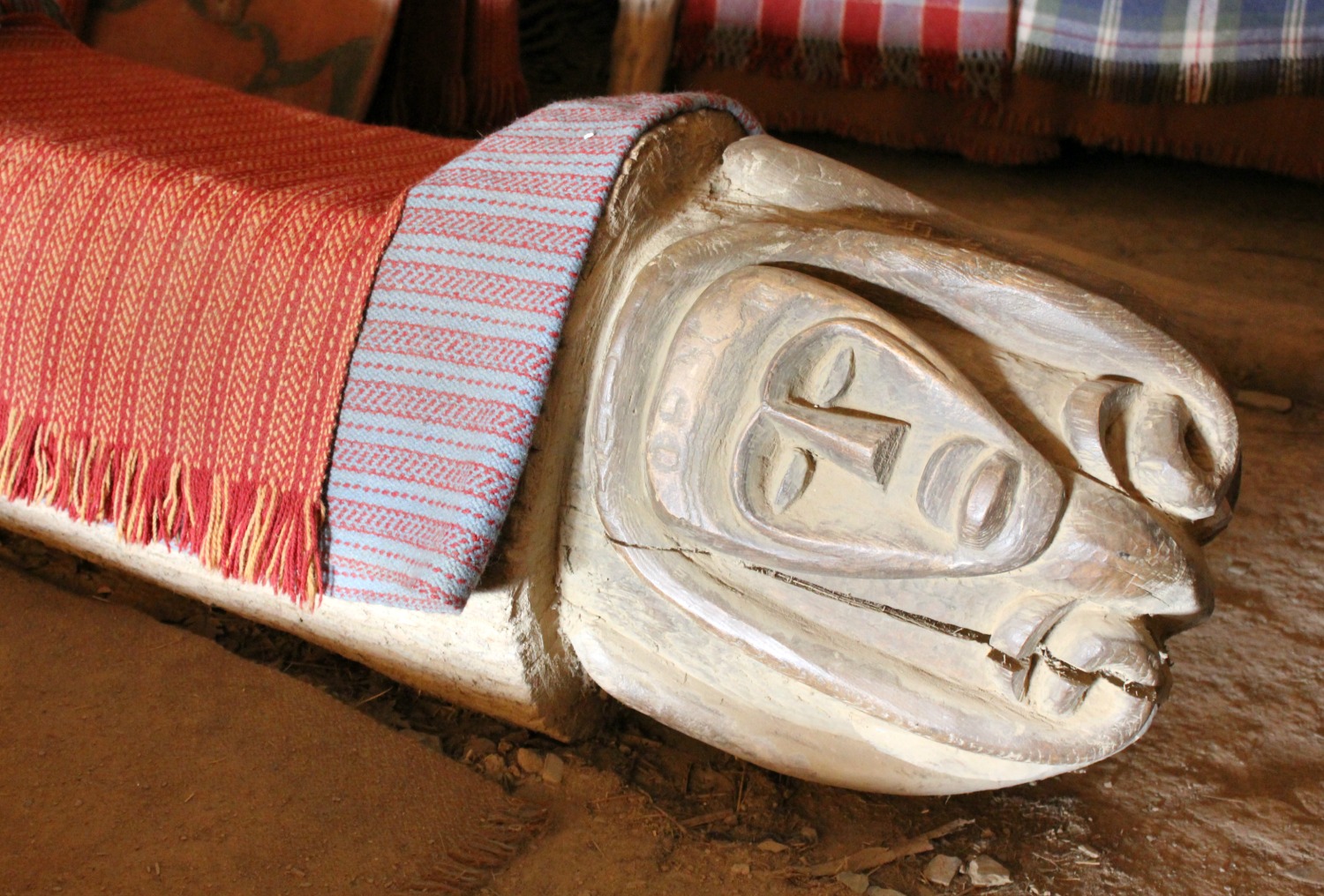 A carved face on the end of a rough wooden bench in a roundhouse at Castell Henllys Iron Age village in Wales - one of my three top days out in Pembrokeshire with kids