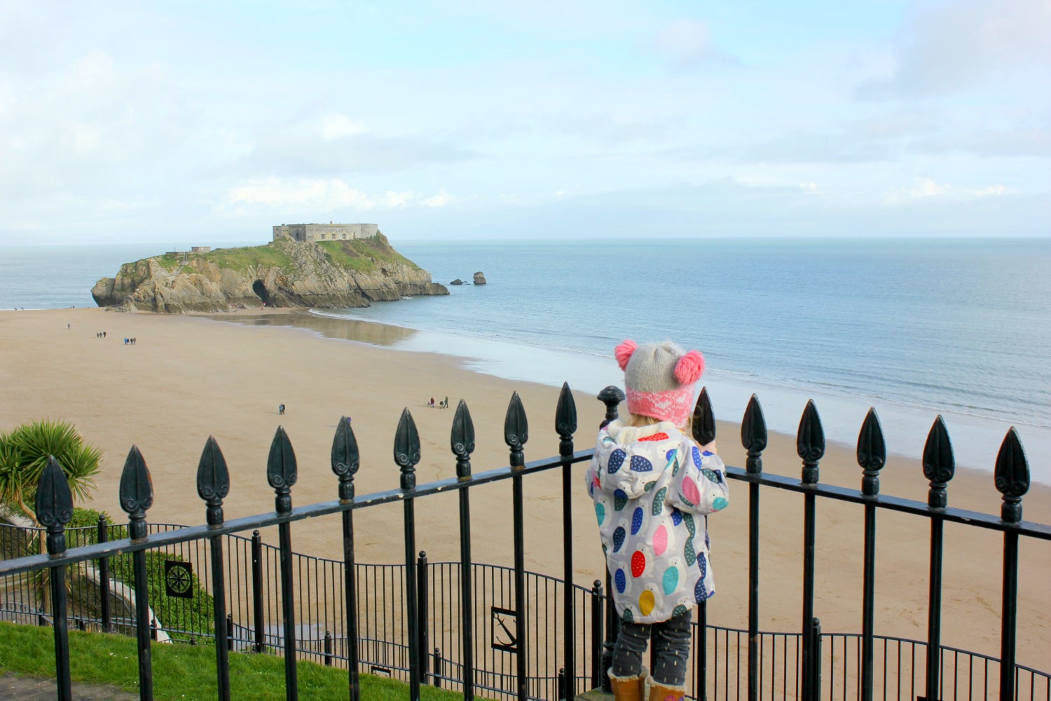 A girl looks out across the beach at Tenby to St Catherine's Fort - one of my three top days out in Pembrokeshire with kids