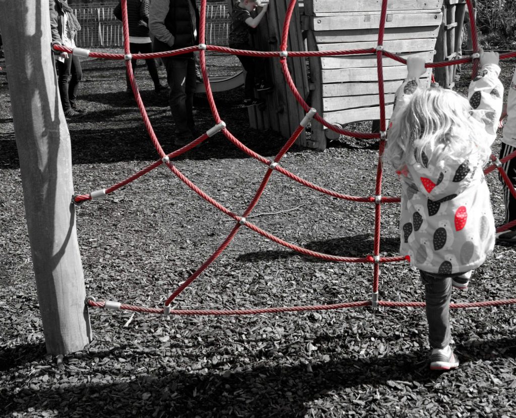 The red of the climbing net in the playground and my daughter's coat against a monochrome background at Cliveden - a day out in photos testing my Fujifilm X-A3 mirrorless camera