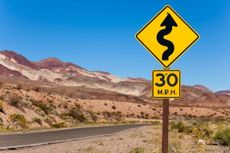 An open road in the middle of nowhere, a yellow warning sign against the blue sky - my three top family road trip ideas