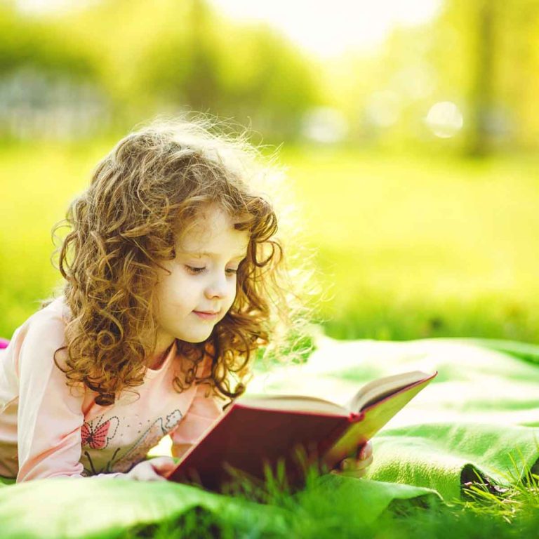 A girl sits with a book in a field - let literature inspire even a simple stroll with my top days out with kids who love books