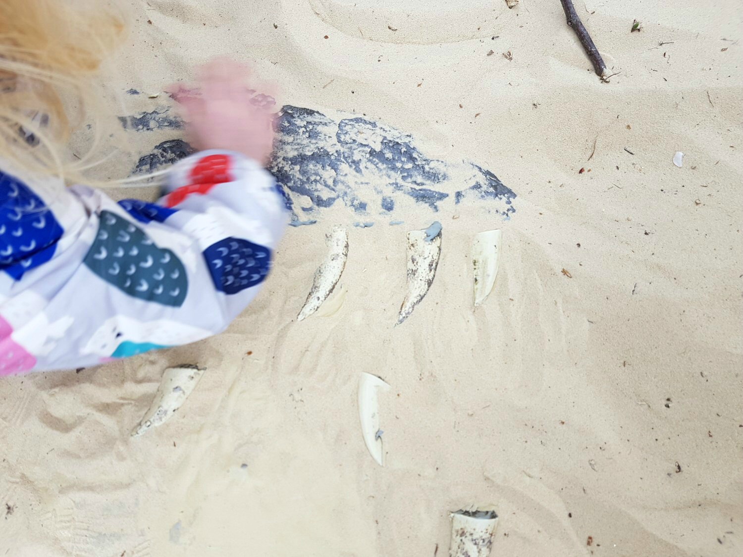 A girl uncovers dinosaur 'bones' in the excavation pit - discovering the Jurassic Kingdom dinosaurs in Osterley Park, London before their UK tour