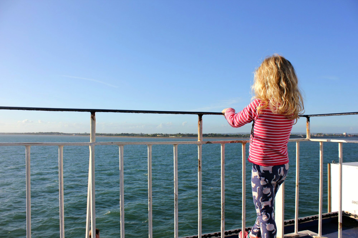 Girl peers over the railings on deck on the ferry between Portsmouth and the Isle of Wight - hunting the Isle of Wight dinosaurs