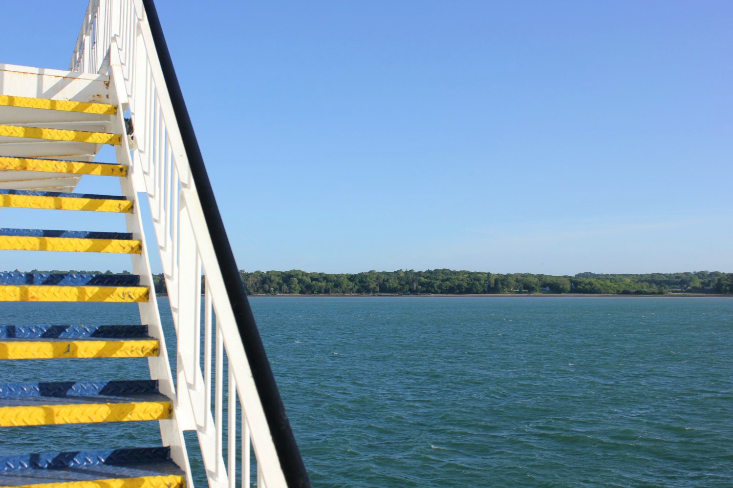 View of the yellow steps and white rail of the stairs on the deck of our ferry, with the sea behind on our way for a family holiday in the Isle of Wight