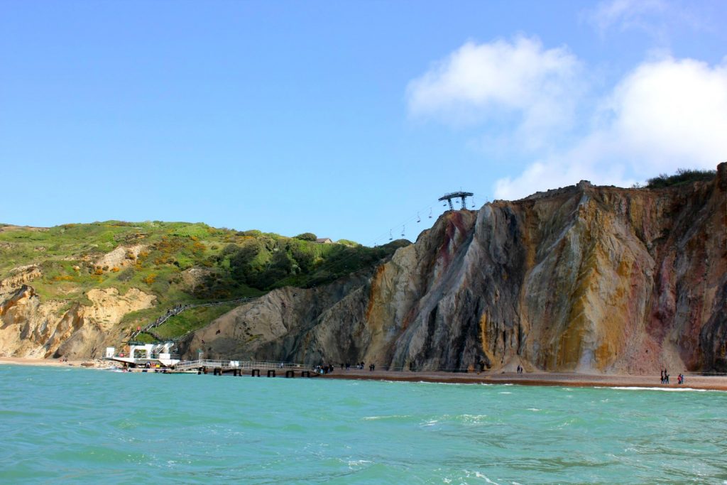 A view onto Alum Bay and the turquoise sea, with the chairlift in the background - discovering the Isle of Wight coast