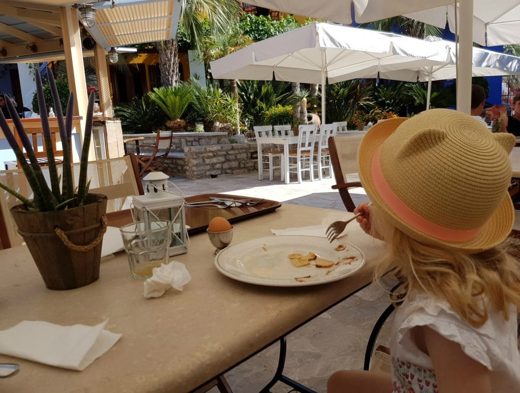 My daughter eating breakfast in the courtyard at Iapetos Village on Symi in Greece - my Iapetos Village Symi review