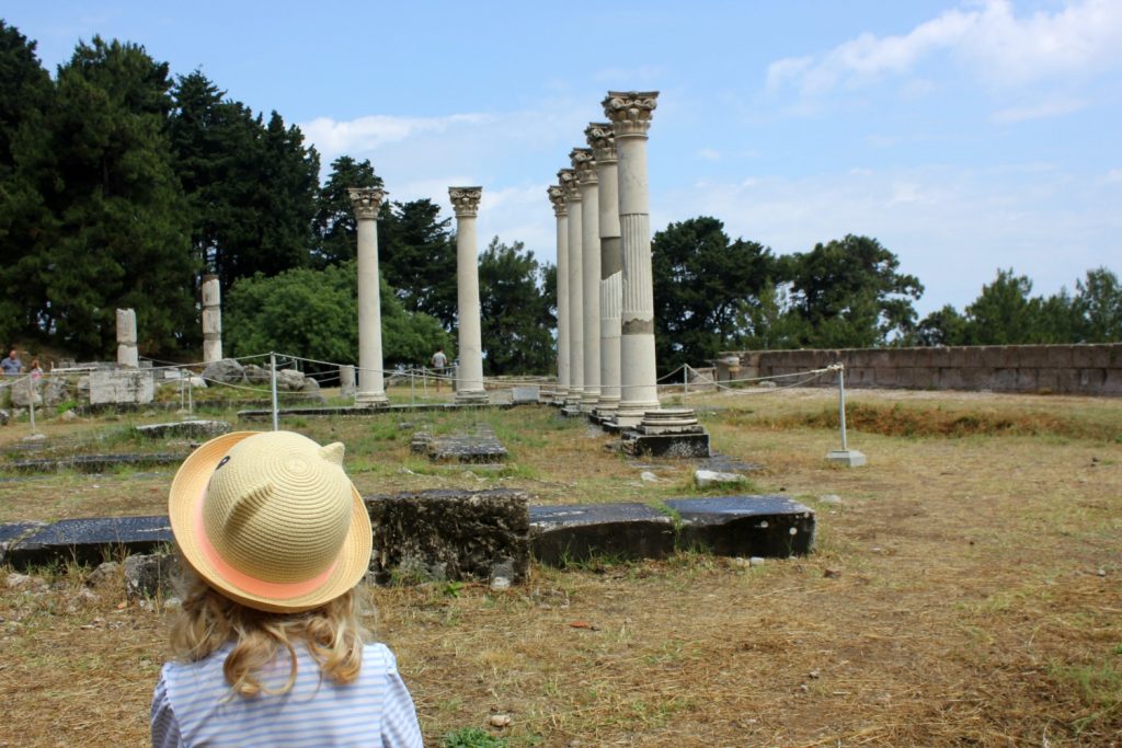 My daughter looking at the columns at the Asklepion on Kos - one of my 13 reasons to choose Greek island hopping with kids