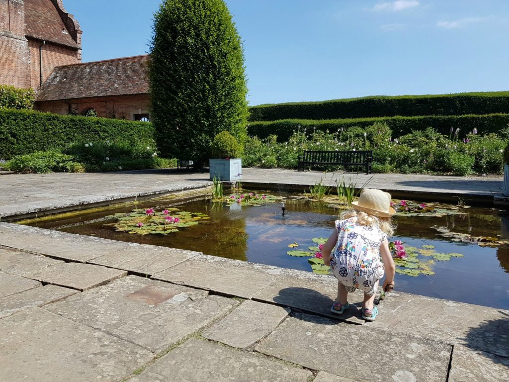 My daughter by a pond in the gardens at Port Lympne - my Rhino Lodge review