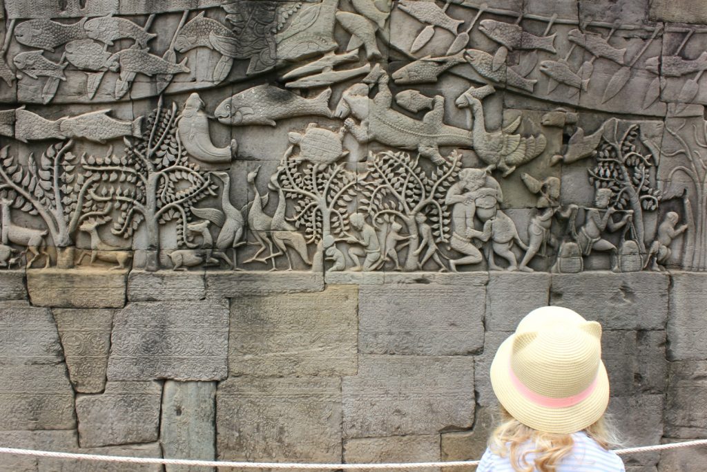 My daughter looks at one of the intricately carved reliefs of the Angkor temples in Cambodia, this at Bayon - one of the temples I visited in Angkor with kids
