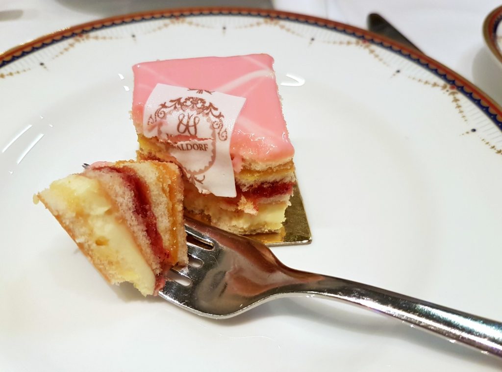 A forkful of one of the cakes on a china plate - my review of Waldorf Hilton afternoon tea