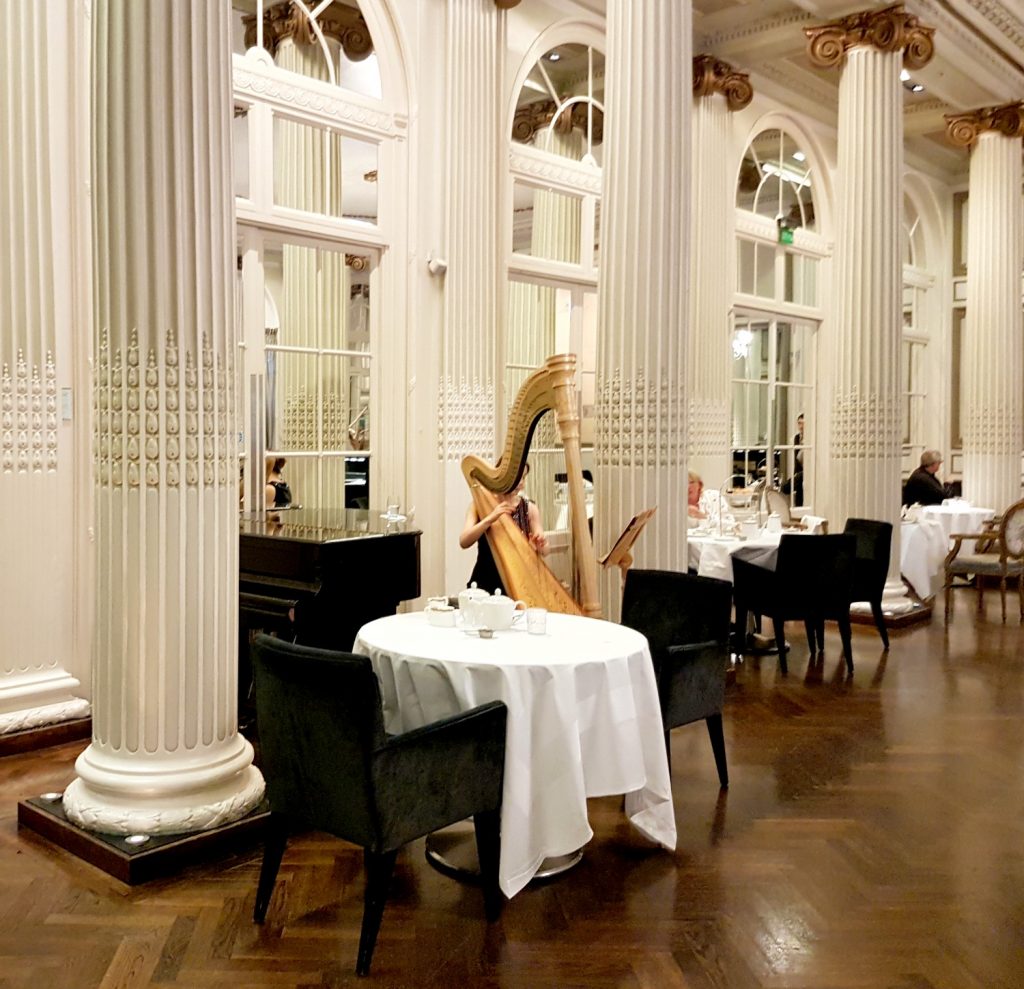 A harpist plays by the cream pillars in Homage - my review of Waldorf Hilton afternoon tea