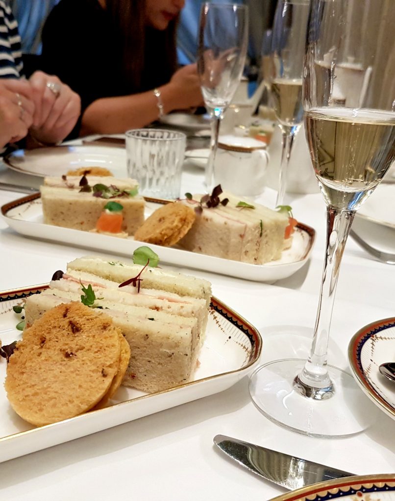Sandwiches and a glass of champagne on the table - my review of Waldorf Hilton afternoon tea