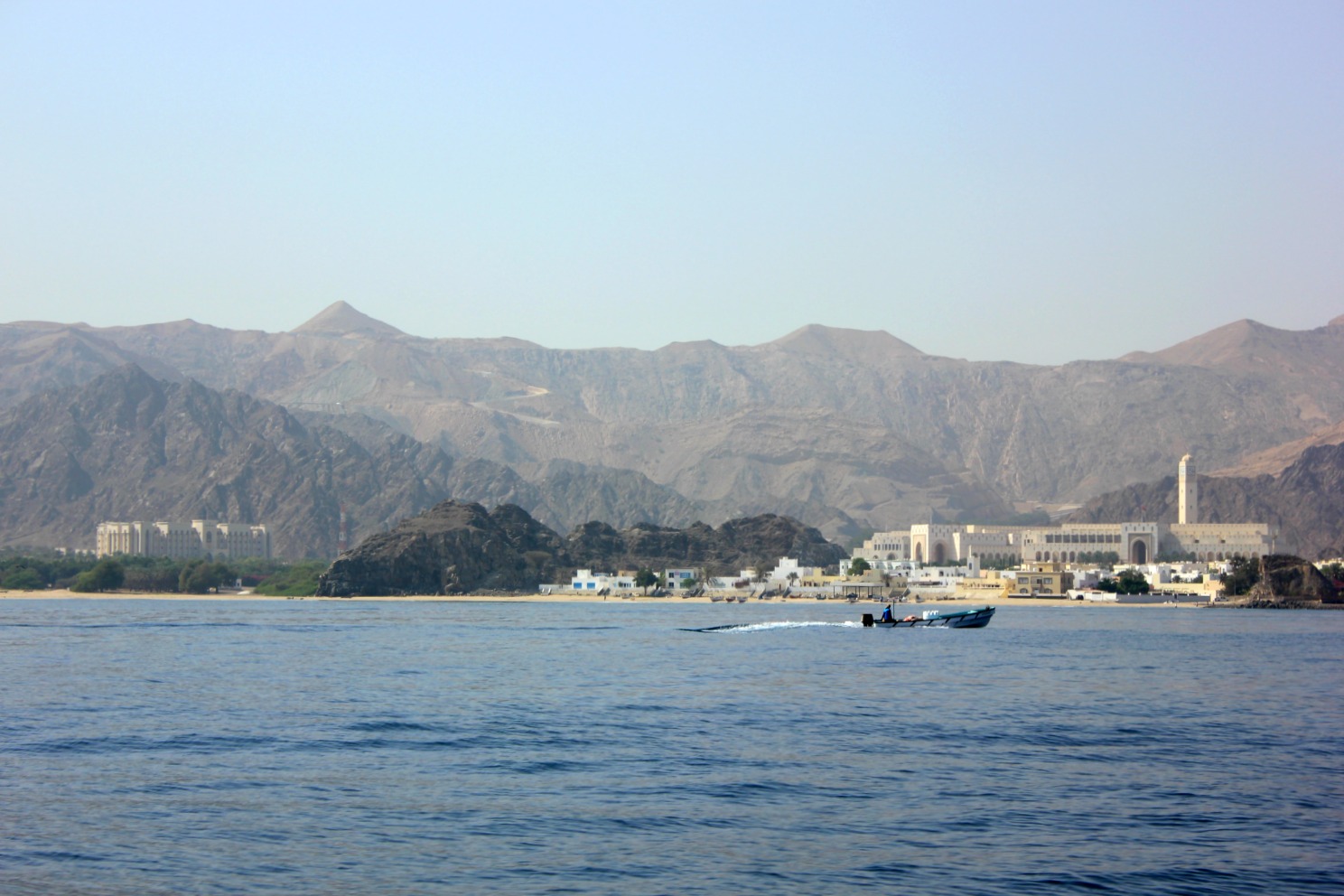 A view from the sea back on to Muscat and the mountains during our dolphin spotting trip, including a boat on the waves - my tips for spending 24 hours in Muscat, Oman with kids