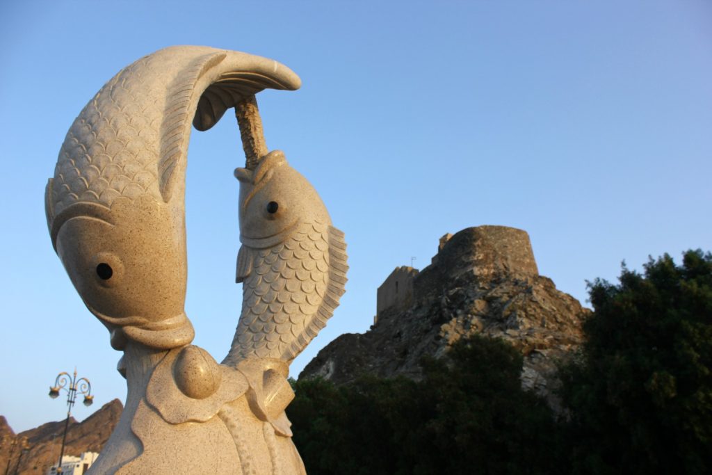 Fish sculpture on the waterfront at Mutrah, or Muttrah, with the fort on a hill in the distance behind - my tips for spending 24 hours in Muscat, Oman with kids