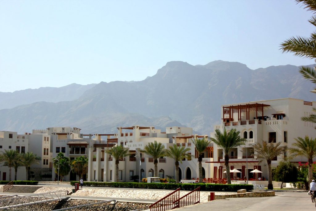 The white buildings at the marina of As Sifa with the mountains behind near Muscat, Oman - my nine reasons to visit Oman with kids