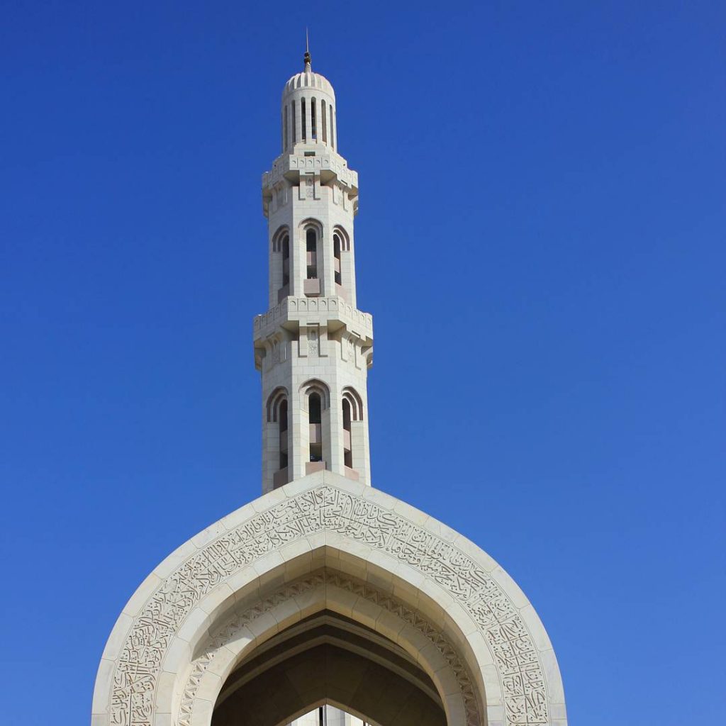 A view of one of the ornate white minarets of the Sultan Qaboos Grand Mosque in Muscat Oman - the beautiful architecture is one of my nine reasons to visit Oman with kids