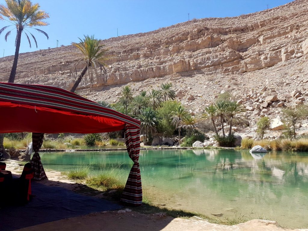 A red tent set up by the waters of Wadi Bani Khalid in the Hajar Mountains in Oman - my nine reasons to visit Oman with kids