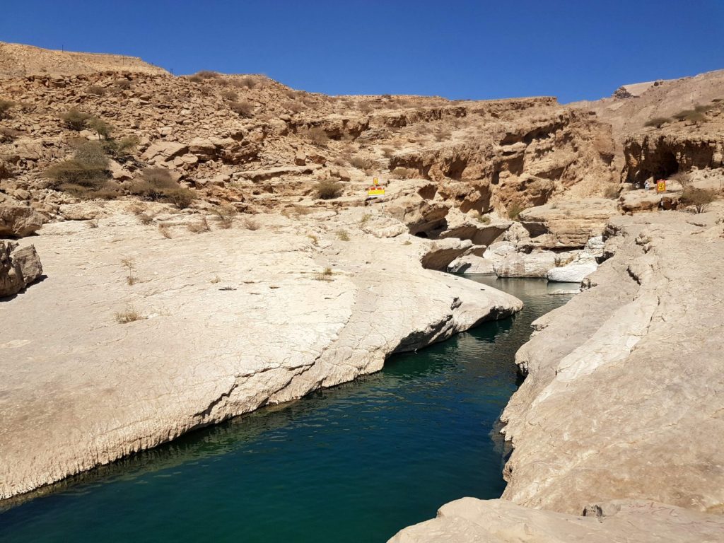 The waters of Wadi Bani Khalid curving through the rock of the Hajar Mountains in Oman - my nine reasons to visit Oman with kids