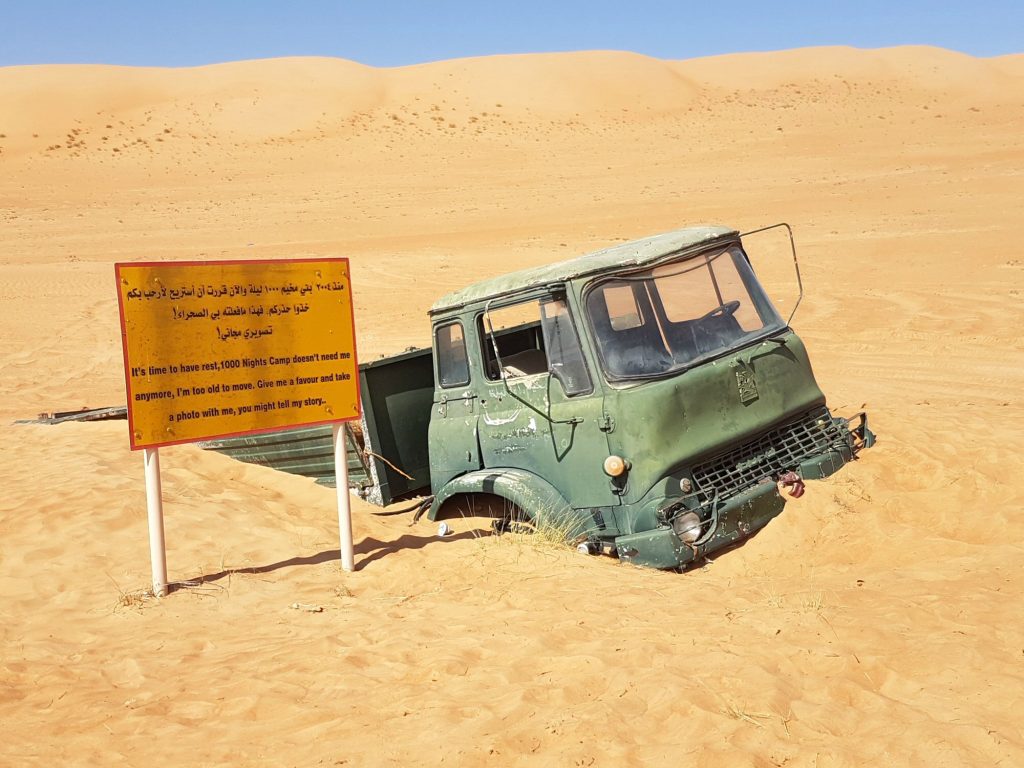 A half buried truck in the sand outside the 1000 Nights Camp at Wahiba Sands in Oman - my nine reasons to visit Oman with kids