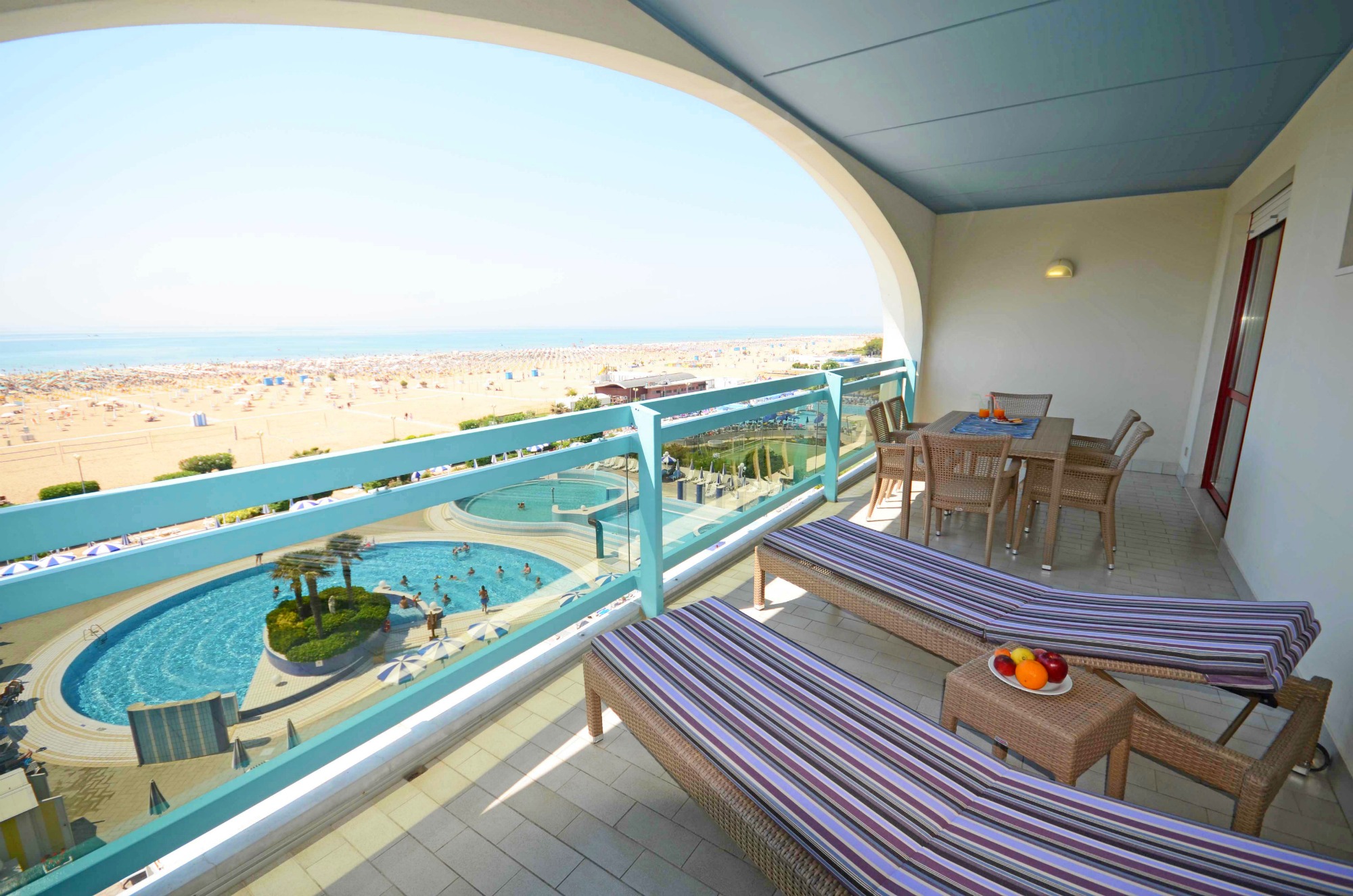 Two sun loungers on the balcony at Imperial Aparthotel in Bibione, looking out across the pool to the beach and the sea why it's worth considering Bibione with kids if you visit Italy's Veneto region