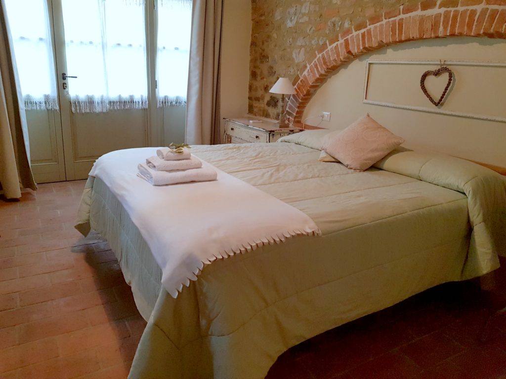 A double bed with brick arch over the headboard at Villa Le Capanne near Volterra in Tuscany - my review of the perfect big family villa in Tuscany, Italy